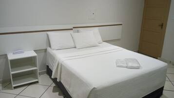 A standard hotel room with a bed, a nightstand, and a wooden door.