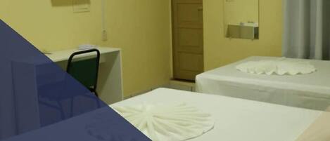 A hotel room with two beds, a desk, a chair, a television, and a door.