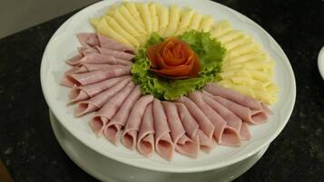 A plate with neatly arranged slices of ham, cheese, and a decorative rose made of lettuce and carrot.