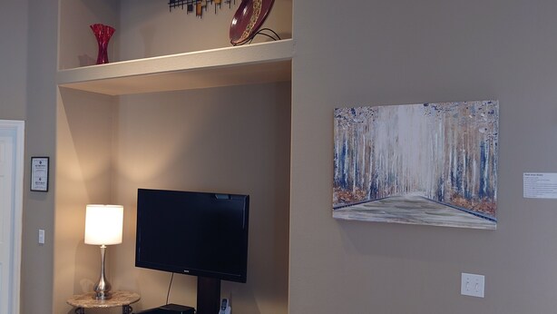 A living room with a television, lamp, and artwork on the wall. - Florida Villa - 6 miles from Disney (Davenport)