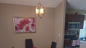 A dining area with a glass table, black chairs, a red table runner, and a chandelier. - Florida Villa - 6 miles from Disney (Davenport)