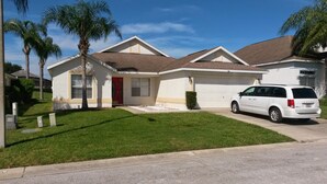 A single-story house with a red door, a garage, and a white van parked in front. - Florida Villa - 6 miles from Disney (Davenport)