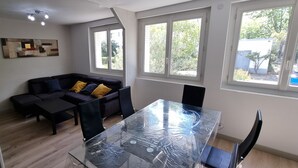 A modern living room with a glass table, black sofa, and a painting on the wall. - Elegant T3 near the center of Montpellier (Montpellier)