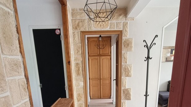 A hallway with a wooden floor, stone walls, and a hanging light fixture. - Elegant T3 near the center of Montpellier (Montpellier)