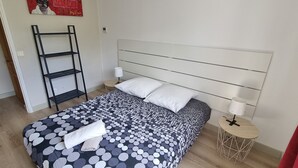 A bedroom with a bed, a nightstand, a lamp, a ladder, and a small table. - Elegant T3 near the center of Montpellier (Montpellier)
