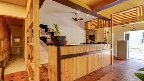 Un mostrador de recepción de madera con un ventilador de techo, un lavamanos pequeño y una estantería llena de libros.