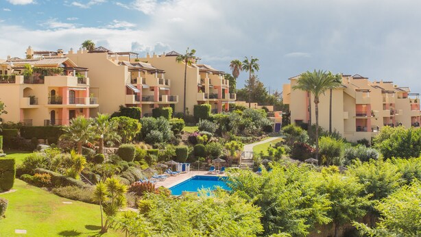 Een resort met meerdere gebouwen, een zwembad en weelderige begroeiing.