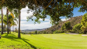 Een golfbaan met een helder uitzicht op het omliggende landschap, inclusief heuvels en bomen.