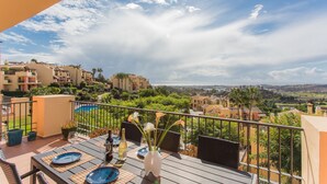 Een terras met een eettafel, stoelen en een vaas met bloemen.
