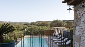 Un espace piscine avec vue sur la campagne, une terrasse en bois et des chaises longues.