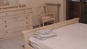 Quarto com cama, penteadeira, cadeira e radiador.