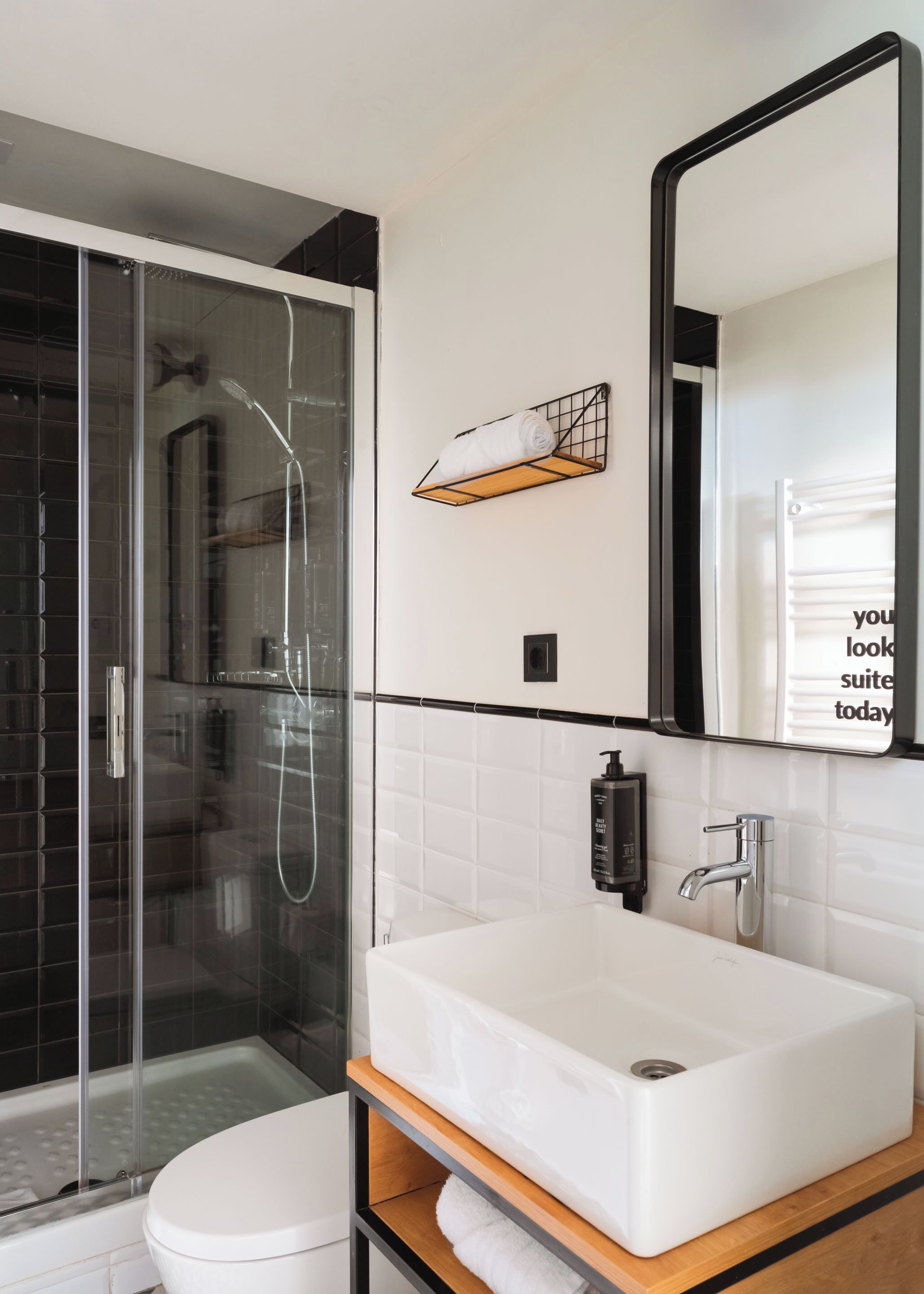 A modern bathroom with a glass-enclosed shower, a white sink, and a mirror.