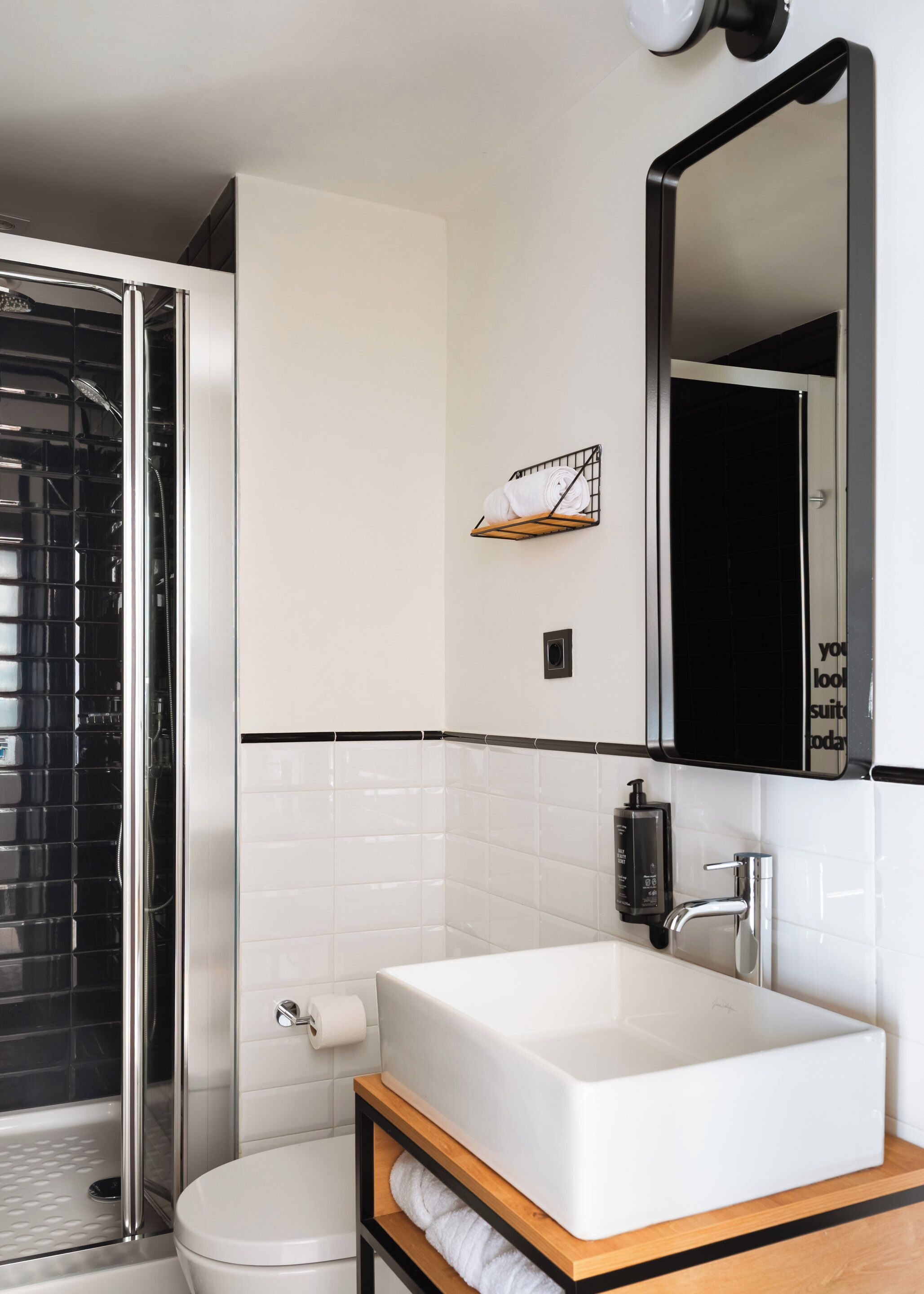 A modern bathroom with a white sink, a mirror, a towel rack, and a shower.