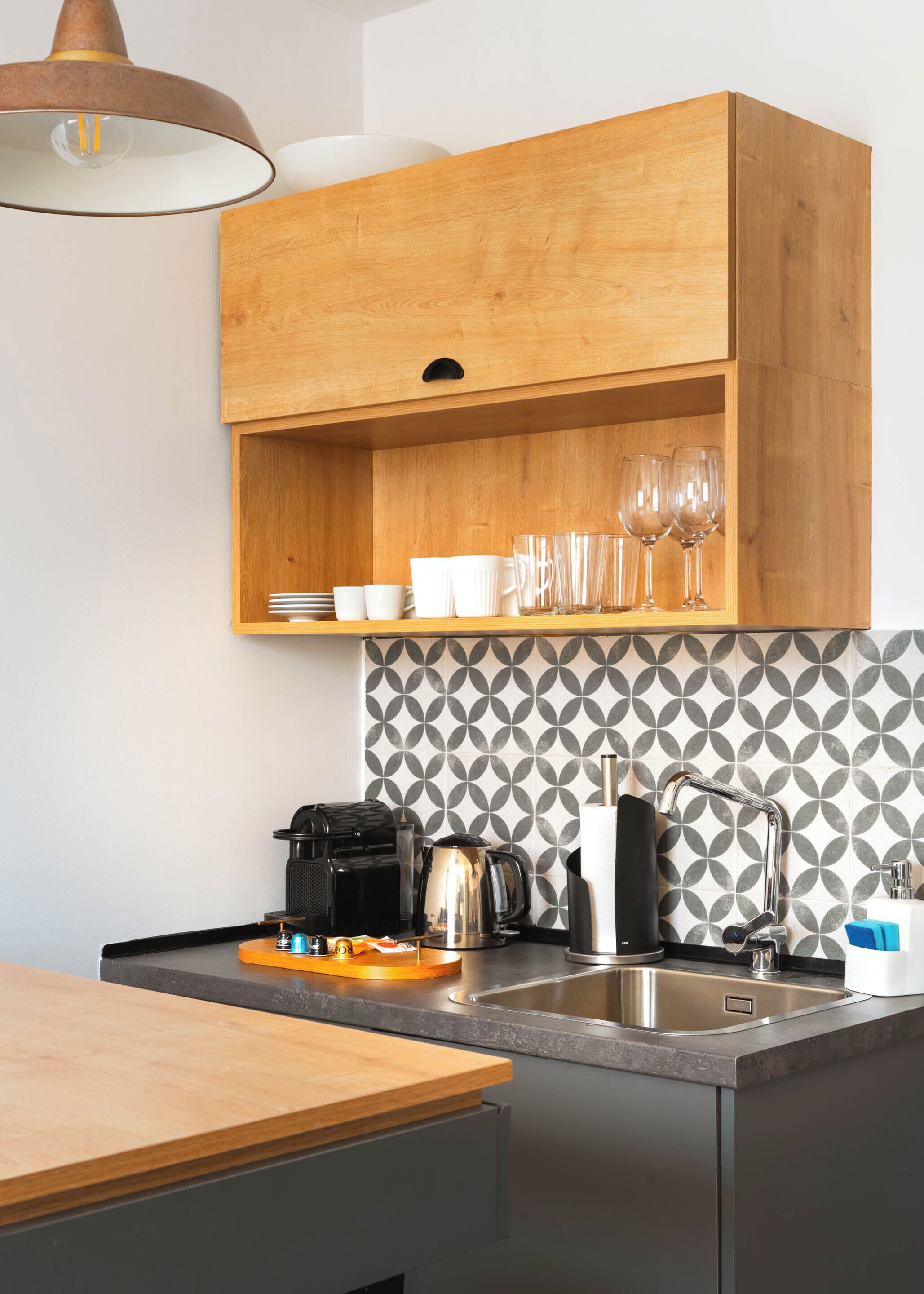 Una cocina moderna con armarios de madera, una encimera, un fregadero y un salpicadero con diseño.