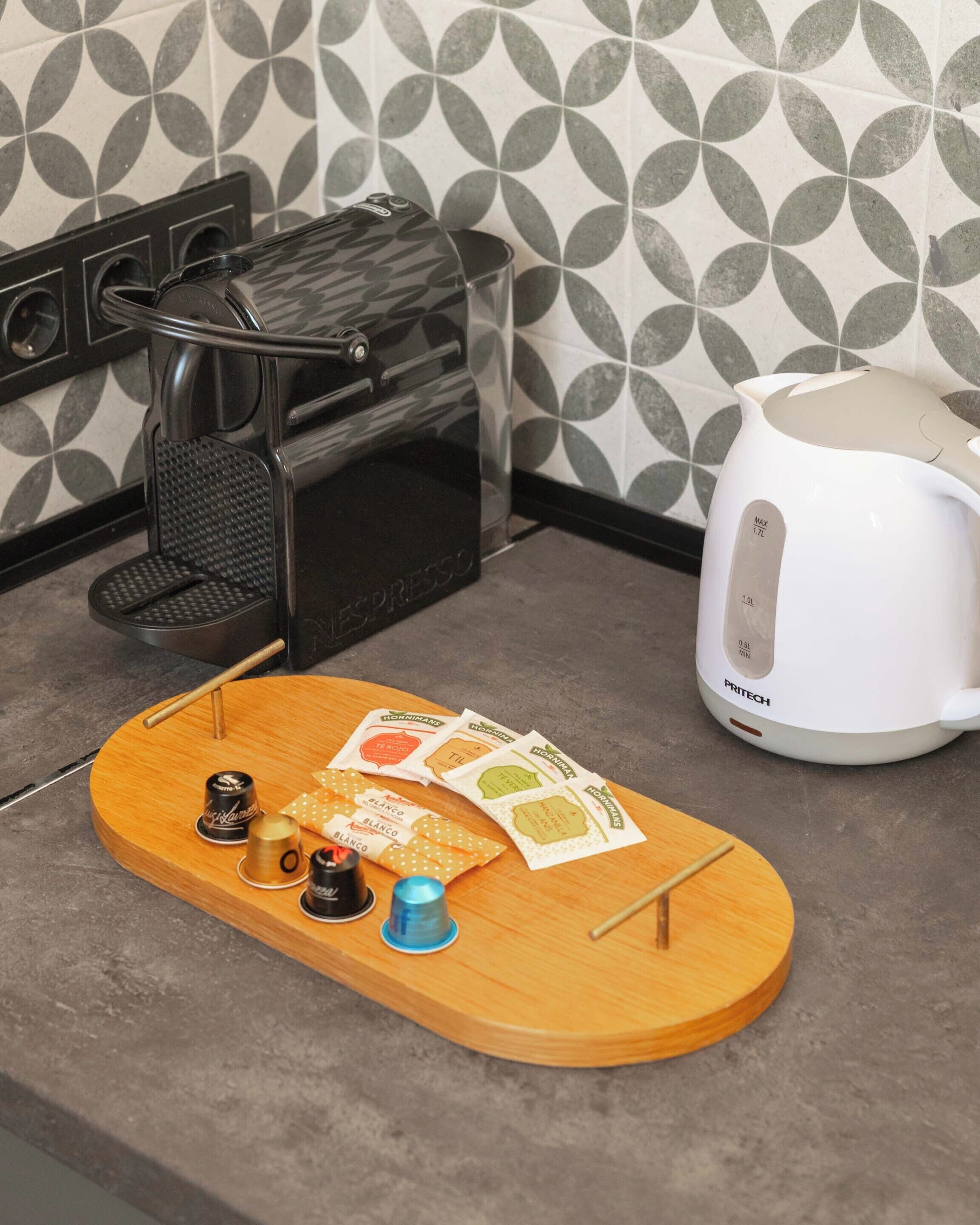 A kitchen with a coffee machine, a toaster, and a wooden tray with coffee pods and a teapot.