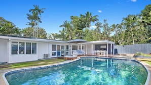 Ein modernes Haus mit Swimmingpool, überdachter Terrasse und umzäunter Garten.