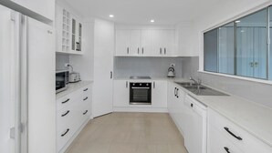 Eine moderne Küche mit weißen Schränken, einem Backofen, einer Mikrowelle und einem Wasserkocher.