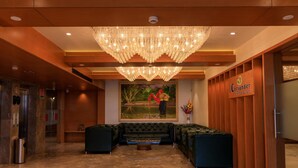 Un hall con candelabro, un cuadro, mostrador de recepción y zona de estar.