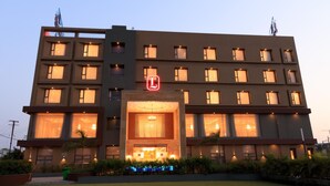 Un hotel de varios pisos con una entrada destacada y un logo visible.