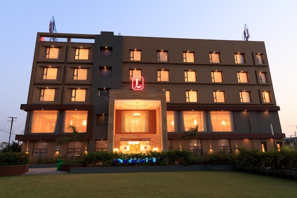 Un hotel de varios pisos con una entrada destacada y un logo visible.
