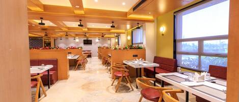 Un restaurante con una barra larga, sillas de madera y mesas.
