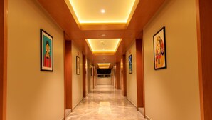 Un pasillo largo e iluminado con cuadros enmarcados en las paredes, que conduce a una habitación al final.
