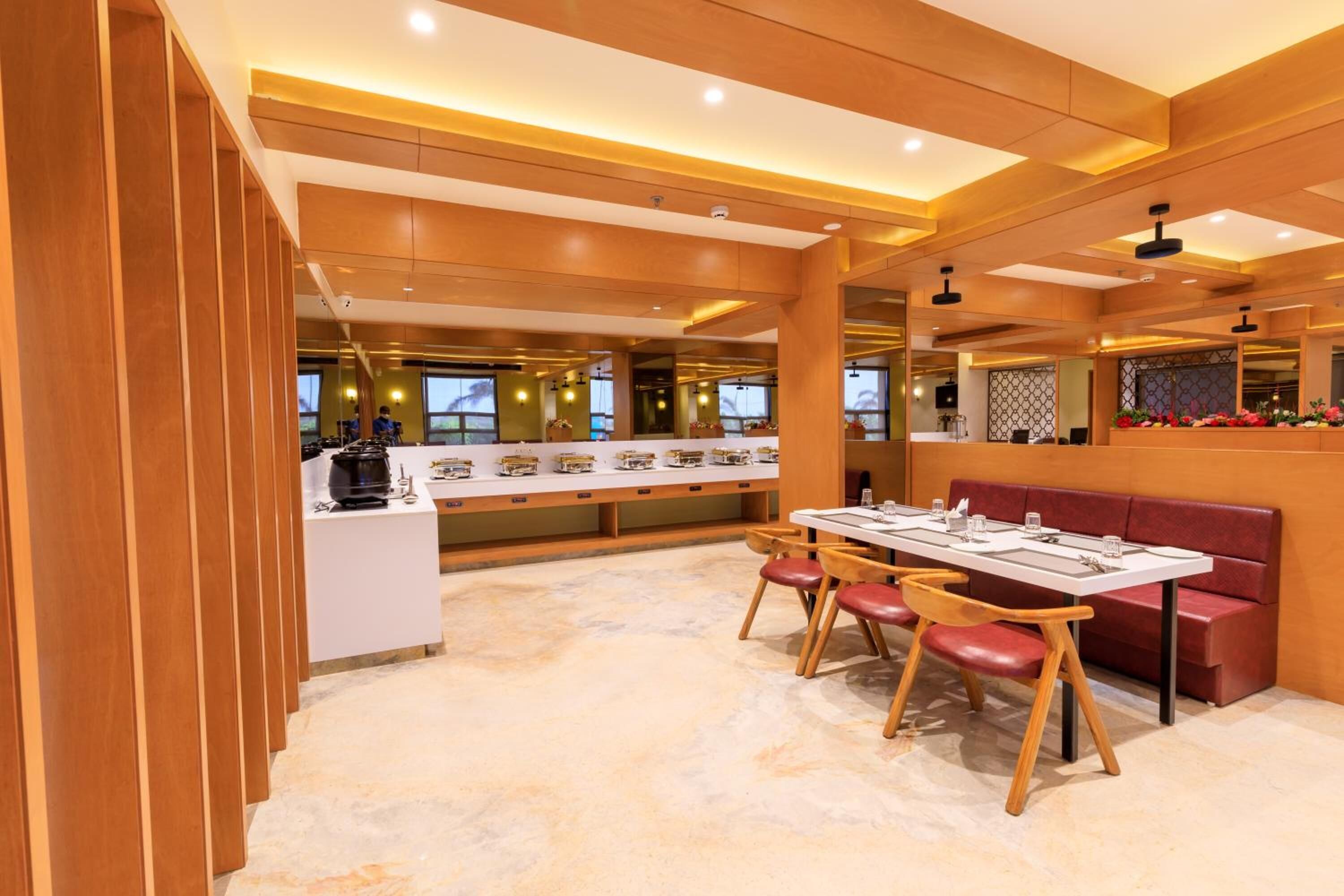 A modern restaurant with a long counter, wooden chairs, and a marble floor.