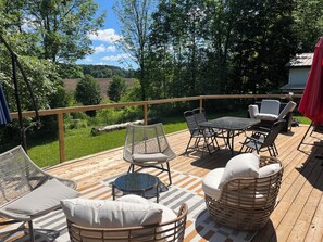 Una terrazza con mobili da esterno, tra cui sedie e un tavolo, che si affaccia su un paesaggio verde.