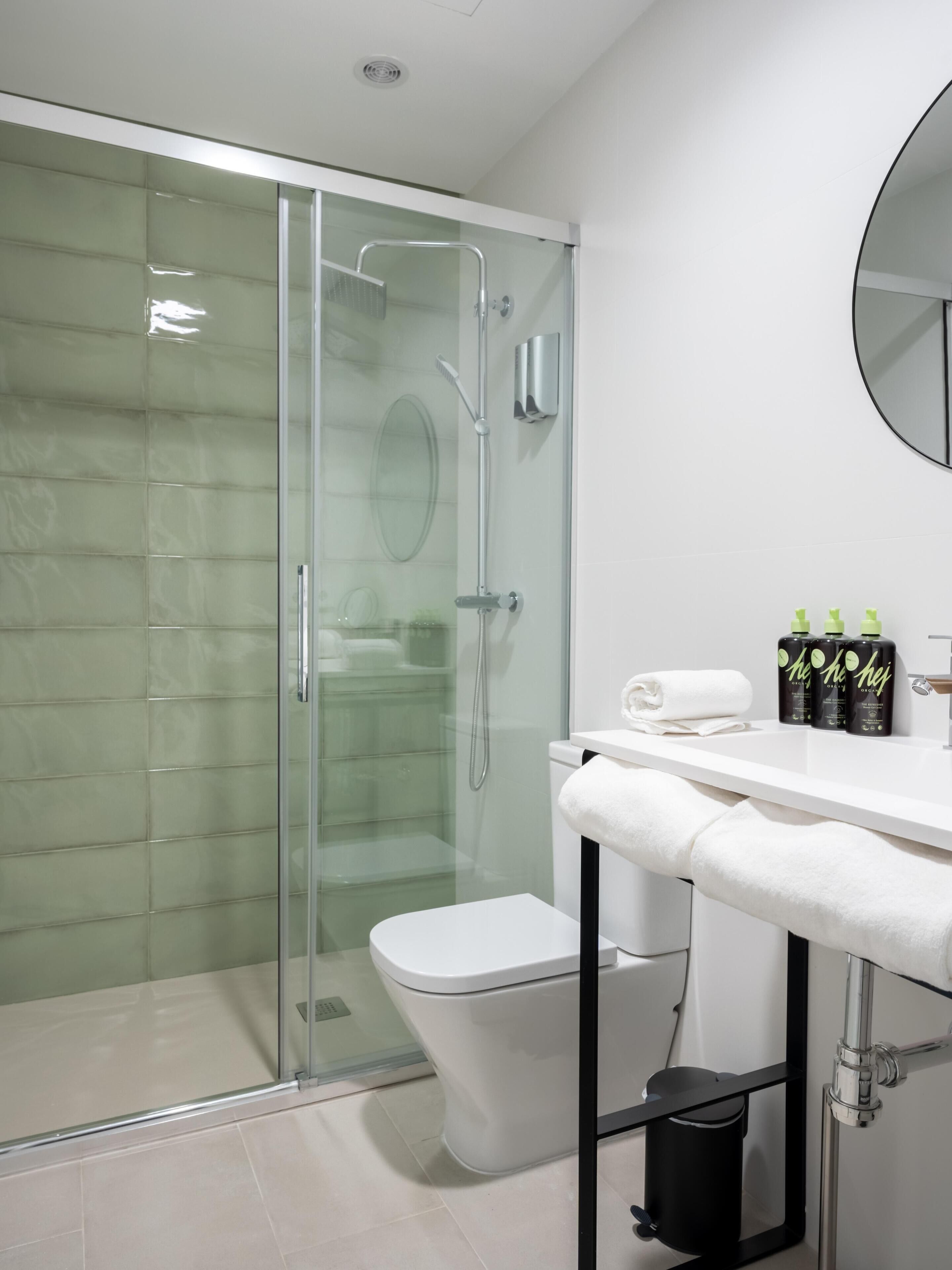 A modern bathroom with a glass-enclosed shower, a white toilet, and a vanity with toiletries.