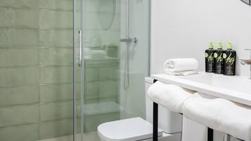 A modern bathroom with a glass-enclosed shower, a white toilet, and a vanity with toiletries.