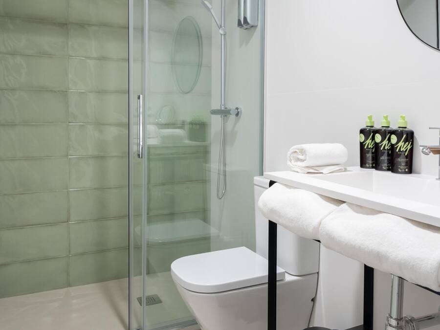 A modern bathroom with a glass-enclosed shower, a white toilet, and a vanity with toiletries.