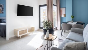 A modern living room with a sofa, a coffee table, a TV mounted on the wall, and a view of the outside balcony. - Limehome Sevilla Calle Torcuato Luca de Tena (Seville)