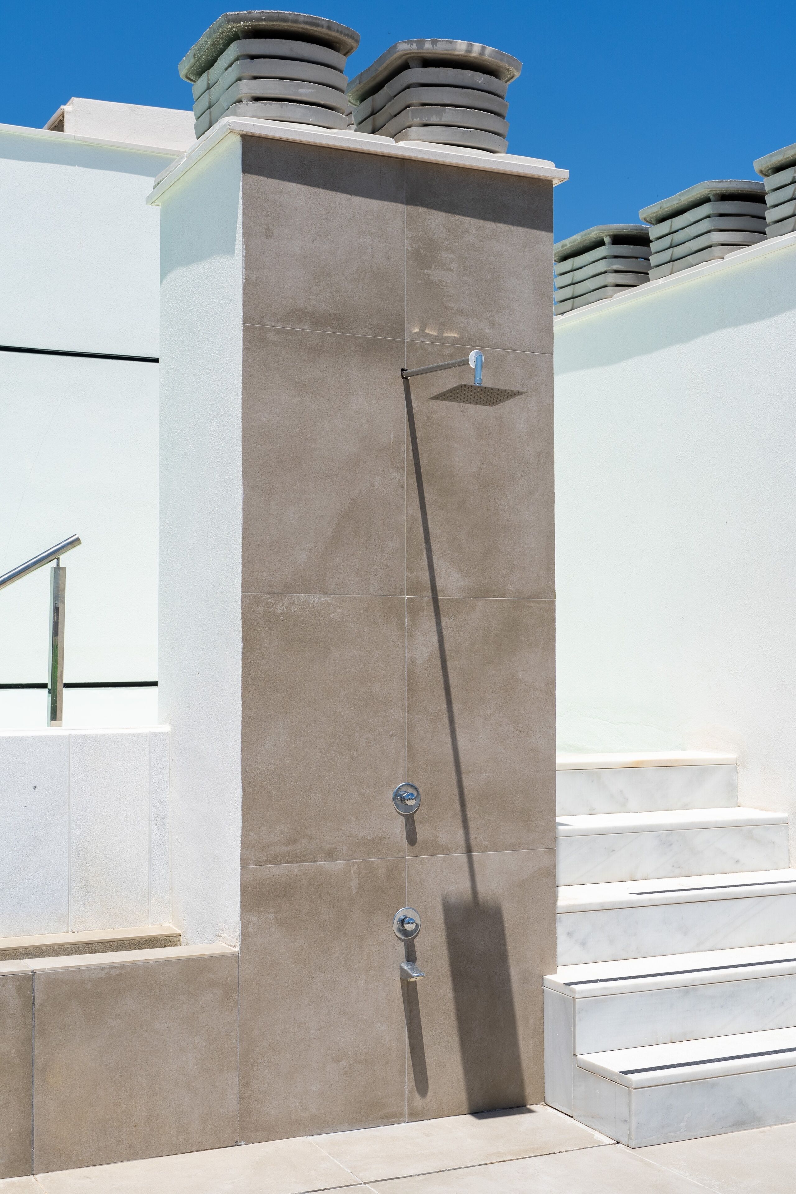 A modern building with a concrete facade, a metal handrail, and a set of stairs leading to a door.