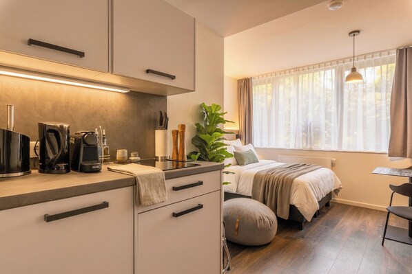 Un dormitorio moderno con cama, mesita de noche y ventana con cortinas.