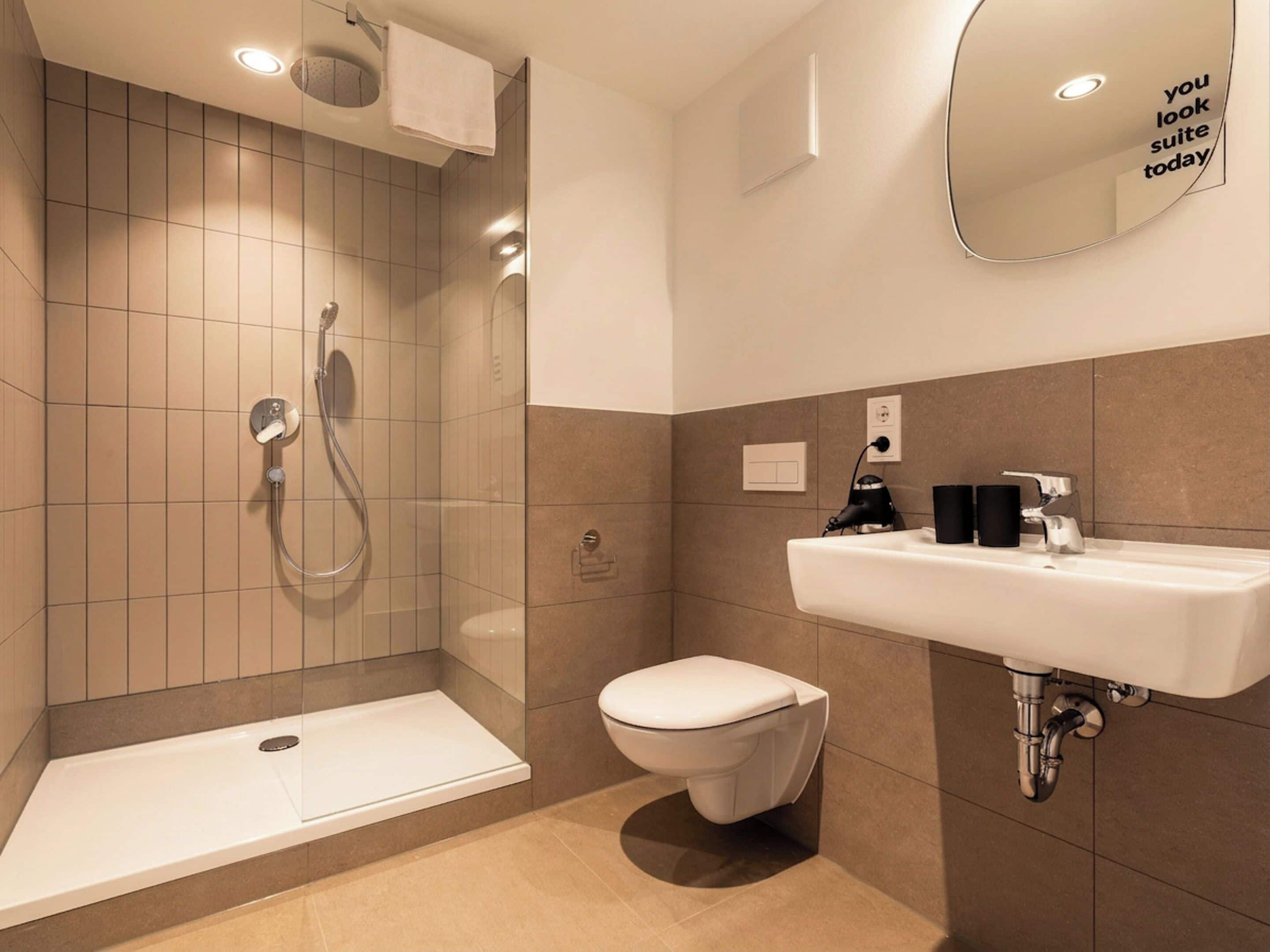 Et moderne badeværelse med bruser, toilet og håndvask.
