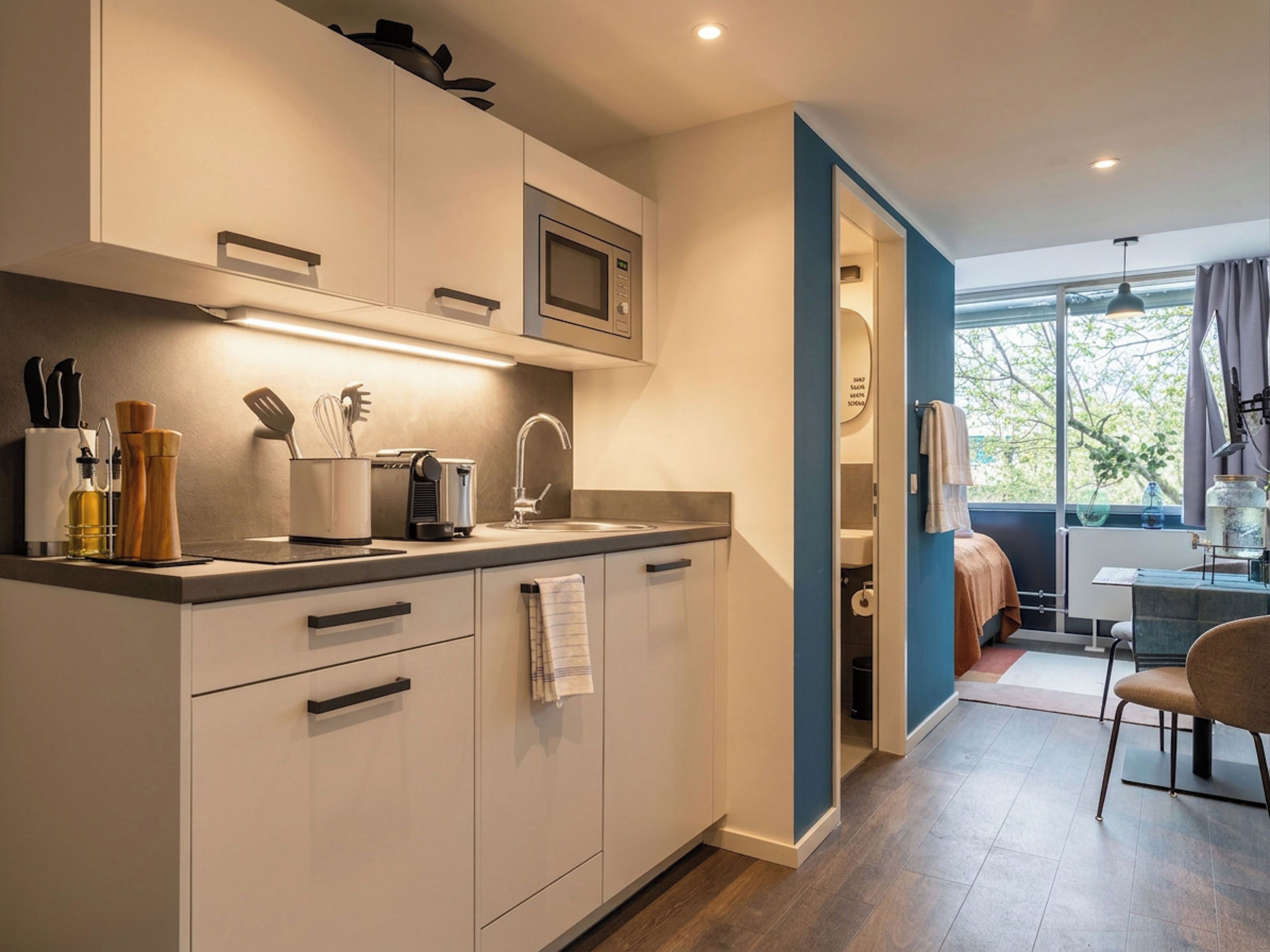 Una cocina moderna con microondas, pileta y diversos utensilios.