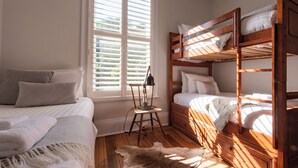 A bedroom with a single bed, a wooden bunk bed, and a desk with a chair.