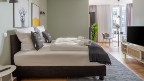 A modern hotel room with a large bed, a TV, a desk, and a view of the city. - Limehome Mönchengladbach Fliethstraße (Moenchengladbach)