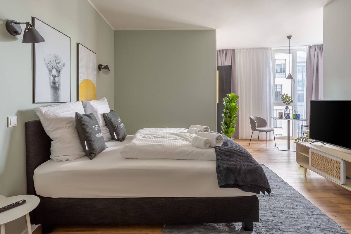 Una moderna camera d'hotel con un letto grande, una TV, una scrivania e vista sulla città.
