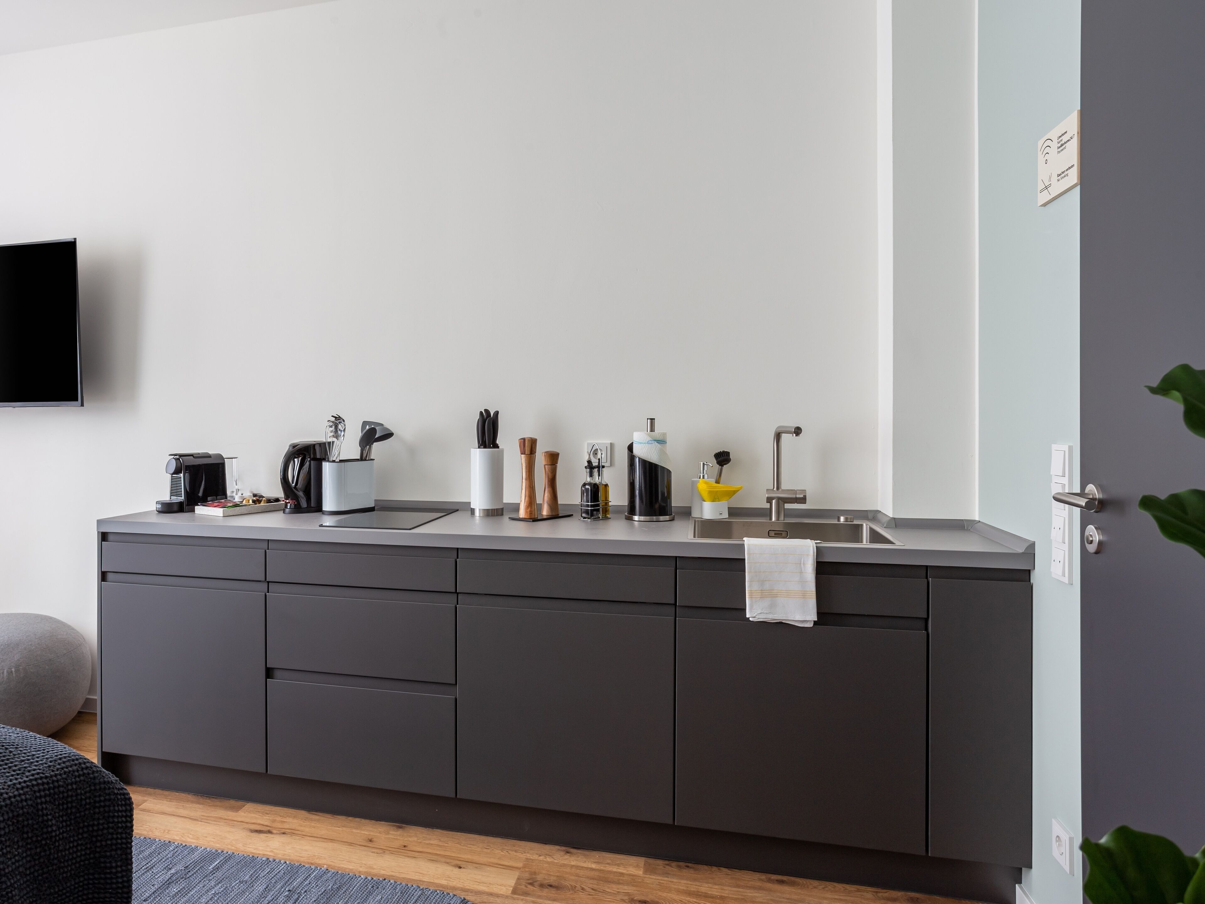 A modern kitchen with a built-in sink, a coffee machine, and various utensils.