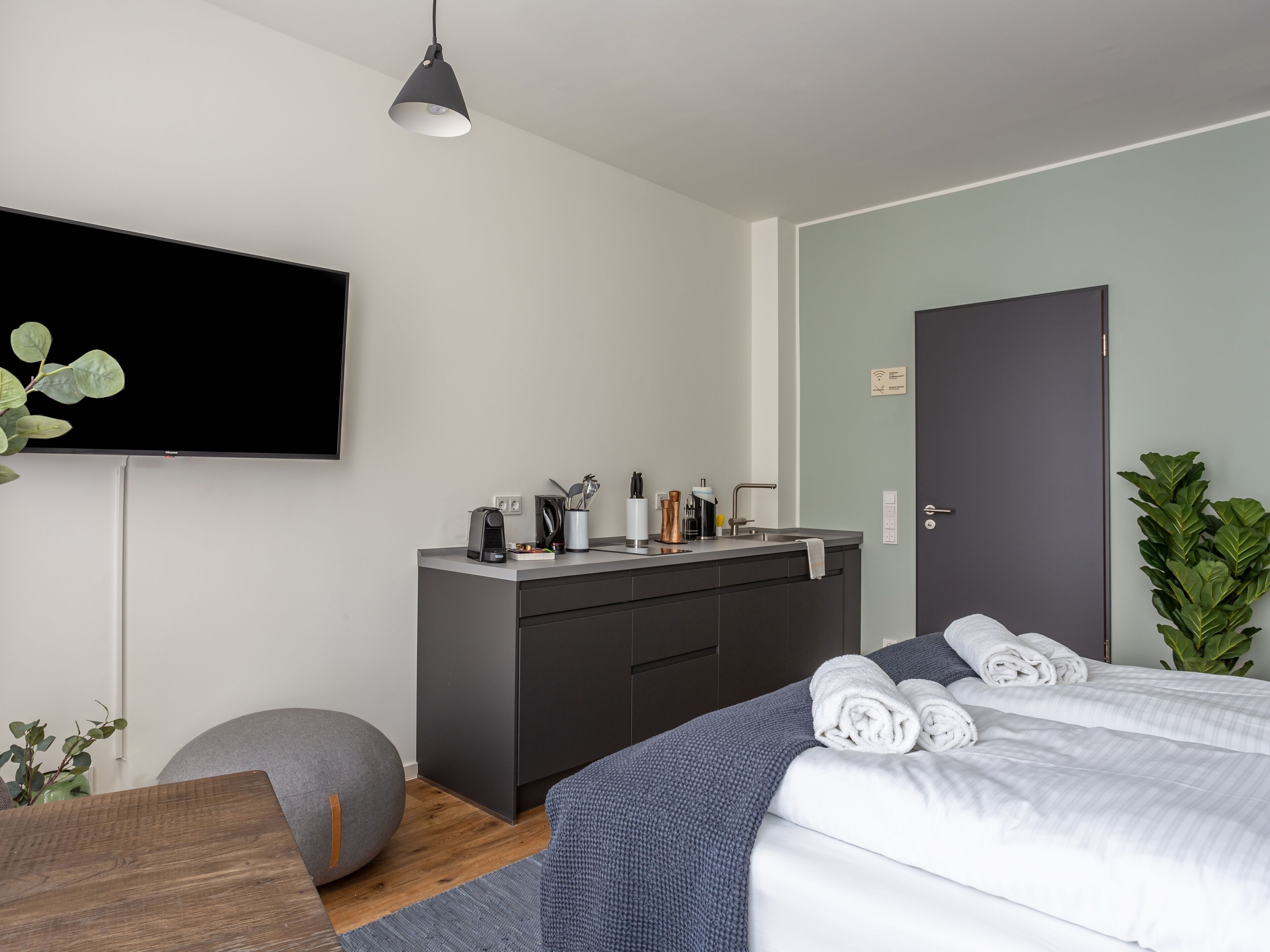 Une chambre à coucher moderne avec un lit, des tables de chevet, une télévision, un bureau et une plante.