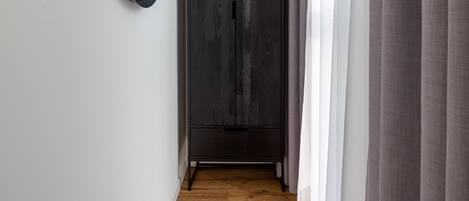 Un pasillo con suelo de madera, un armario oscuro y un espejo redondo en la pared.