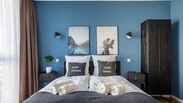 A modern bedroom with a bed, two pillows, a nightstand, a potted plant, and a wardrobe.