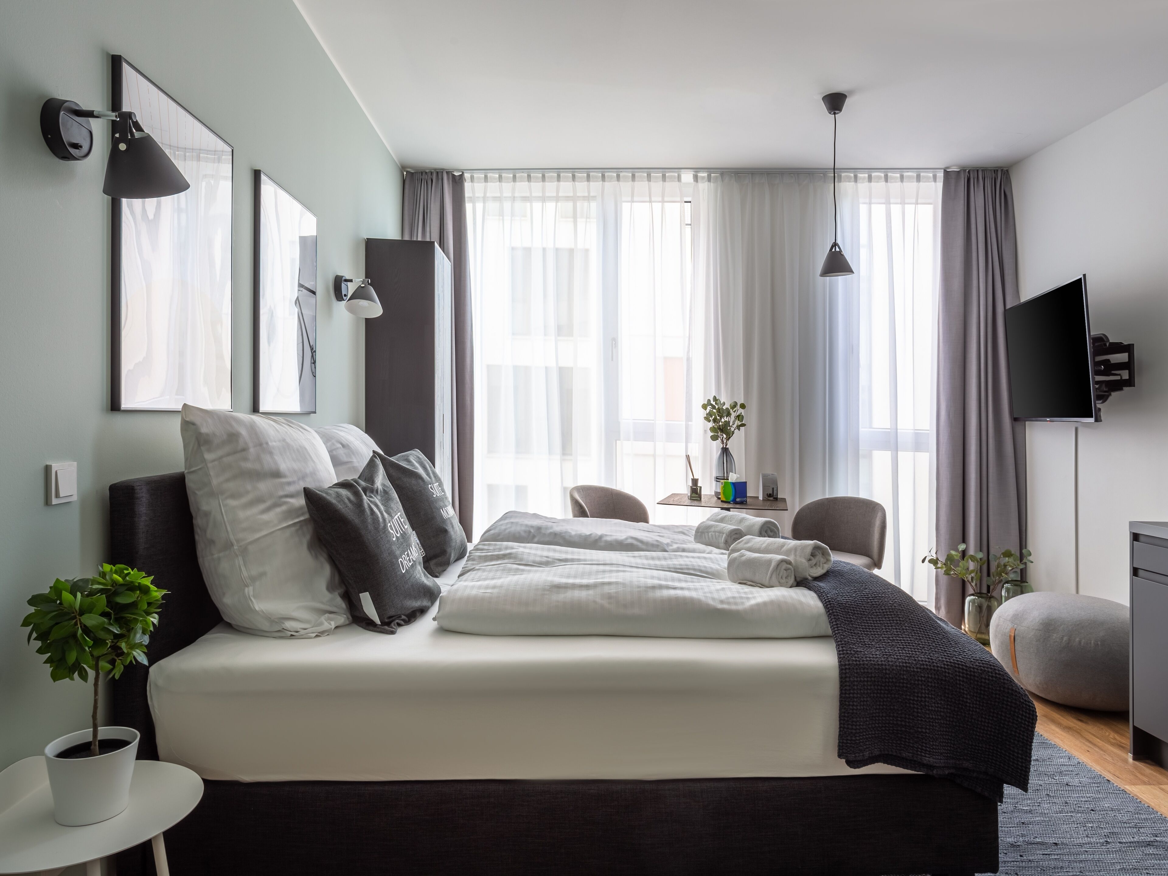 A modern hotel room with a large bed, bedside tables, a desk, and a TV.