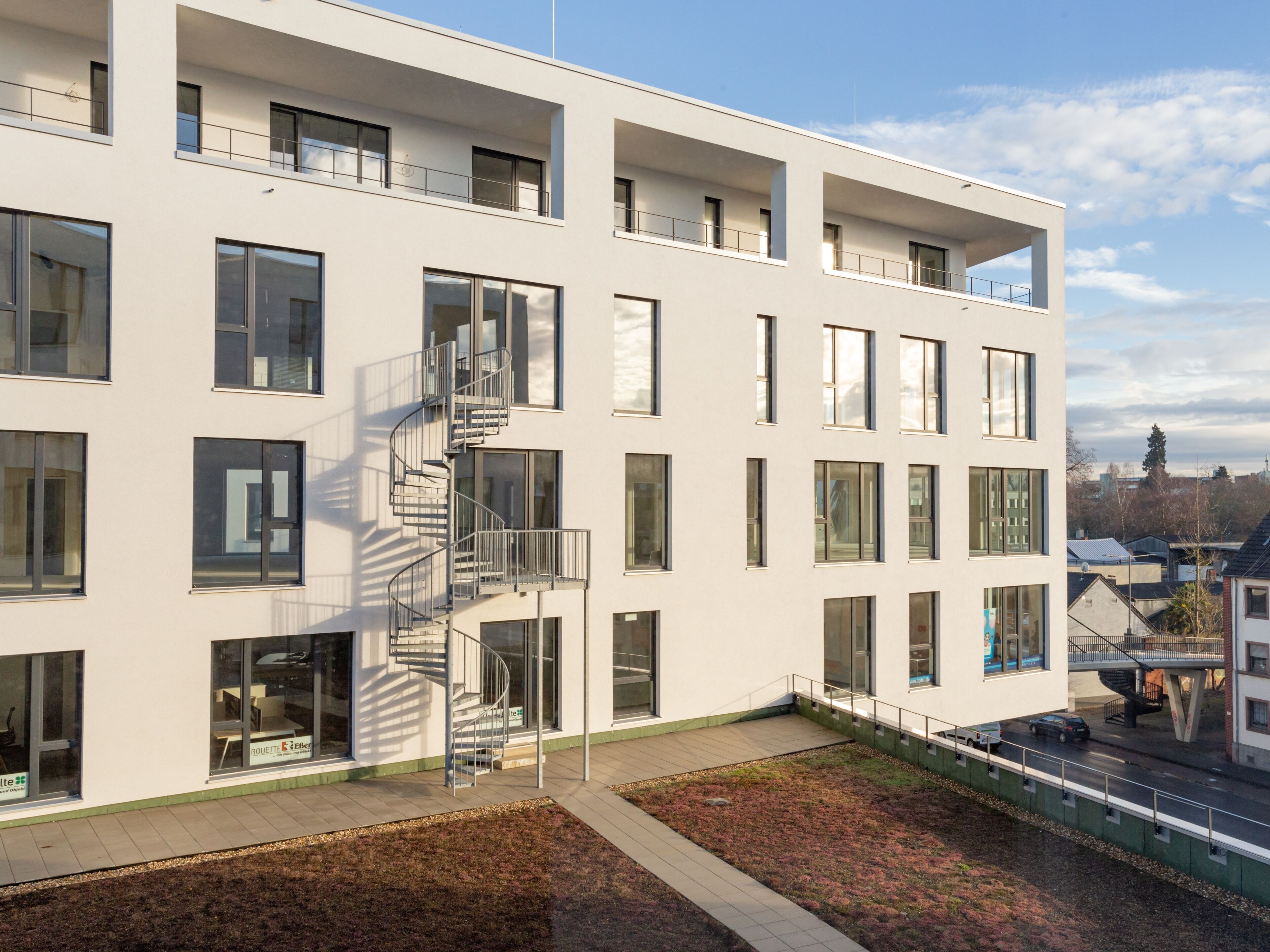 Un bâtiment moderne à plusieurs étages, doté de grandes fenêtres et d’un escalier en colimaçon.