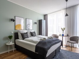 A modern bedroom with a bed, a small table with a plant, and a chair.