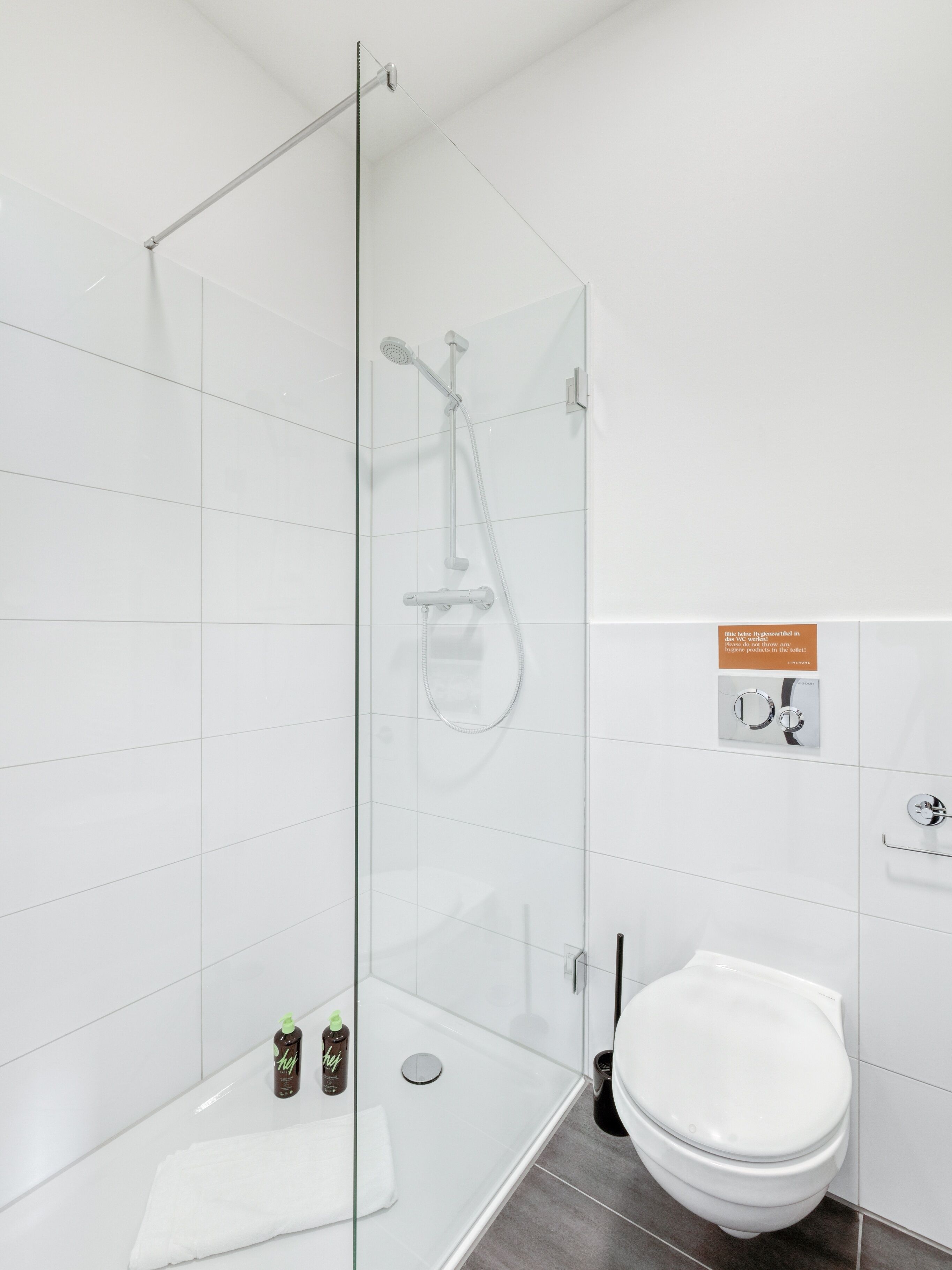 A modern bathroom with a glass-enclosed shower, a toilet, and a sink.
