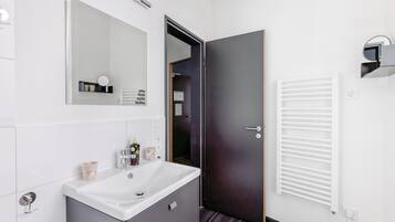 Un baño moderno con un lavabo blanco, un mueble oscuro y un espejo encima.