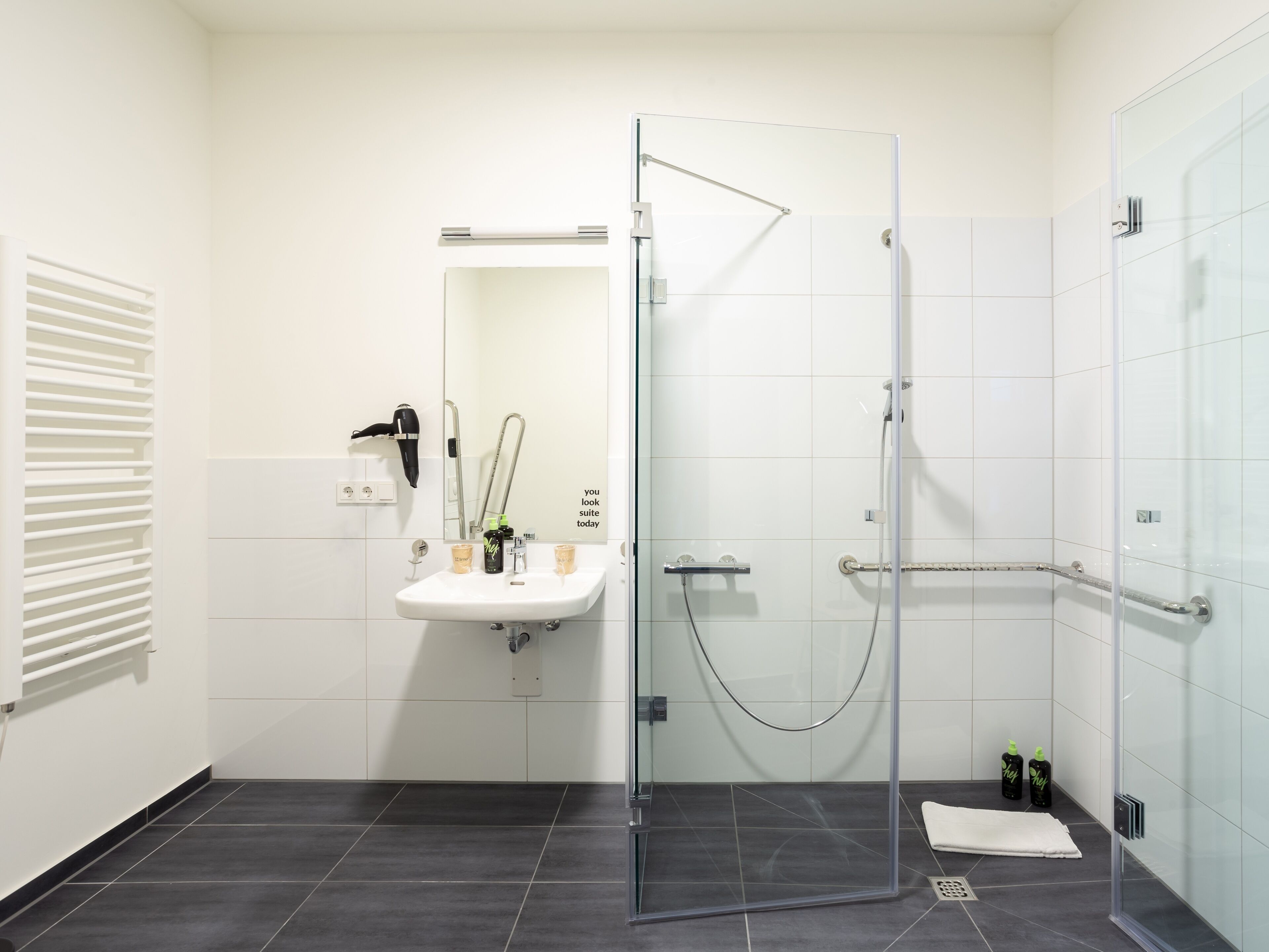 A modern bathroom with a glass-enclosed shower, a white sink, and a mirror.