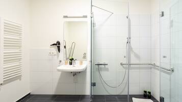 A modern bathroom with a glass-enclosed shower, a white sink, and a mirror.